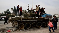 Orang-orang bereaksi saat mereka berdiri di atas tank sambil merayakan setelah pemberontak merebut ibu kota dan mengumumkan bahwa mereka telah menggulingkan Presiden Bashar al-Assad. Assad dikabarkan telah berada di Moskow, Rusia, setelah melarikan diri dari Damaskus, ketika kelompok pemberontak menyerbu dan menguasai ibu kota Suriah tersebut, akhir pekan lalu. Tergulingnya rezim Assad ini terjadi setelah pasukan pemberontak Hayat Tahrir al-Sham (HTS) di bawah pimpinan Abu Mohammed al-Julani melakukan serangan besar-besaran mendadak di sejumlah kota di Suriah. REUTERS/Ammar Awad