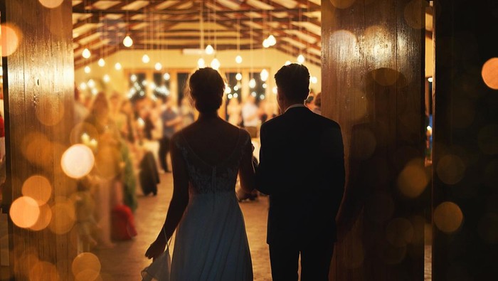 Rearview shot of a young couple arriving hand in hand at their wedding reception