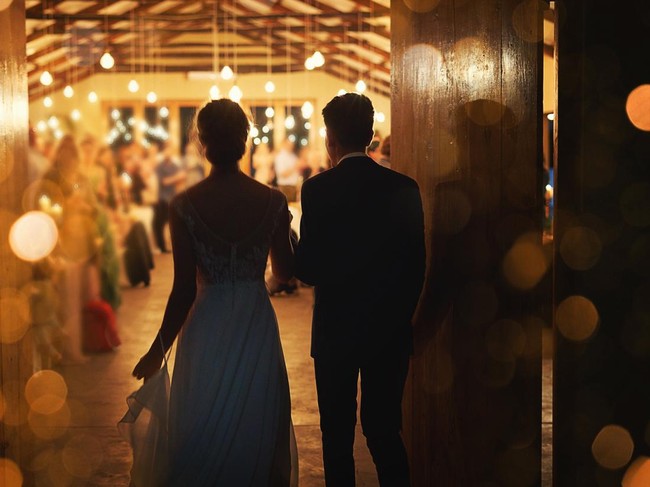 Rearview shot of a young couple arriving hand in hand at their wedding reception