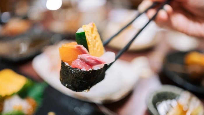 Friends eating at a Japanese restaurant luxury Japanese style cuisine with assorted sushi, seafood ,oysters,sashimi freshly served on the dining table in a restaurant.