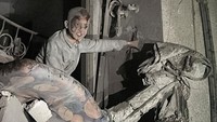 Seorang anak keluar dari reruntuhan bangunan dengan wajah penuh debu. 