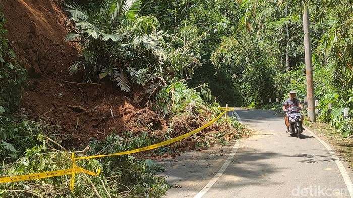 Pengendara melintasi jalan yang tertimbun longsor di Hargotirto, Kokap, Kulon Progo, Jumat (13/12/2024).