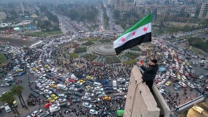Pemandangan udara menunjukkan seorang pria Suriah melambaikan bendera Suriah era kemerdekaan di Lapangan Umayyah di pusat Damaskus pada tanggal 11 Desember 2024. (Photo by Bakr ALKASEM / AFP)
