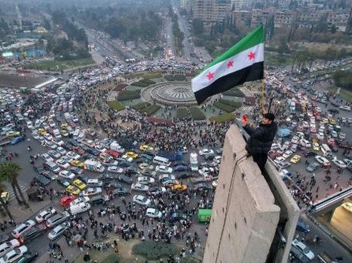 Pemandangan udara menunjukkan seorang pria Suriah melambaikan bendera Suriah era kemerdekaan di Lapangan Umayyah di pusat Damaskus pada tanggal 11 Desember 2024. (Photo by Bakr ALKASEM / AFP)