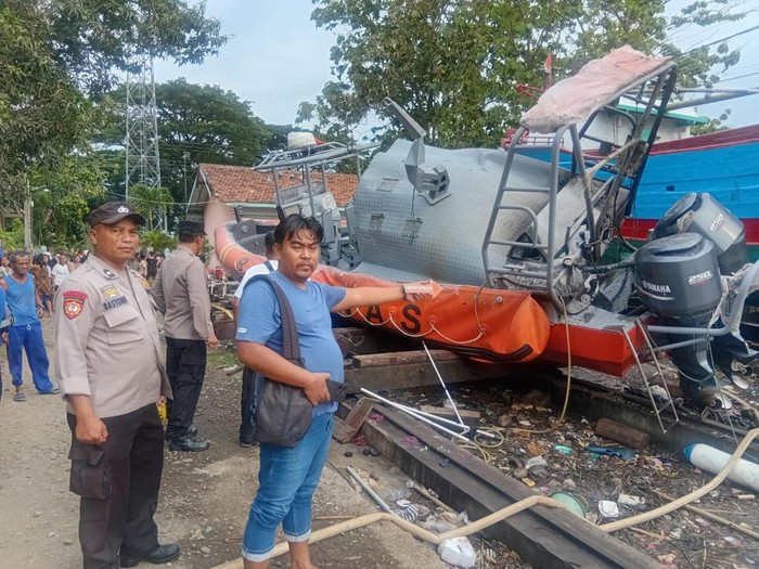 Polisi berjaga di lokasi insiden kapal Basarnas yang meledak saat perawatan rutin di sebuah bengkel di kompleks Pelabuhan Sleko, Kabupaten Cilacap, Jumat (13/12/2024) sore.