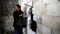 Hiba Zayadin, peneliti Suriah dari kelompok advokasi Human Rights Watch, memeriksa di balik tembok di distrik Tadamon, yang dipenuhi tulang-belulang sisa jasad manusia. 