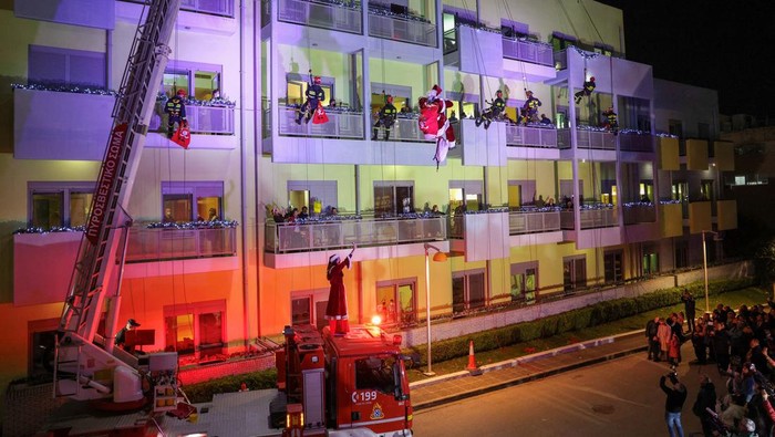 A Greek firefighter, dressed as Santa Claus hands over a Christmas gift to a young patient of the “Marianna V. Vardinoyiannis” Oncology unit of the Aghia Sofia Children’s Hospital in Athens, Greece, December 12, 2024. REUTERS/Stelios Misinas