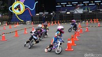Olimpiade Balita Pushbike digelar di lapangan Istora Senayan. Para balita ini pun harus mengendarai sepedanya dengan dorongan kedua kaki melintasi lintasan dan tikungan sebelum tiba di garis finish.