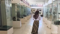 Pengunjung melintasi lorong koleksi busana adat di museum Balanga