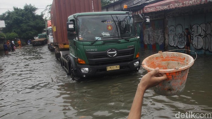 Truk kontainer menembus banjir air laut pasang (rob) di depan gerbang Pelabuhan Sunda Kelapa, Jl Lodan Raya, Jakarta Utara, Minggu (15/12/2024).