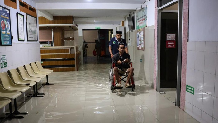 Relawan mengangkat pasien ke mobil ambulans saat evakuasi akibat banjir yang merendam beberapa fasilitas di Rumah Sakit Faisal, Makassar, Sulawesi Selatan, Minggu (15/12/2024). Sedikitnya 26 pasien di rumah sakit tersebut dievakuasi ke beberapa rumah sakit lain yang tidak terdampak banjir sementara pasien lainnya dipindahkan ke ruangan yang masih aman dari genangan air. ANTARA FOTO/Arnas Padda/nym.