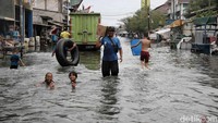 Mereka asyik berenang saat orang dewasa sibuk mengatasi dampak banjir.