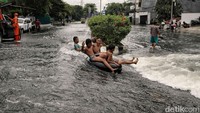 Anak-anak asyik bermain saat banjir rob menerjang kawasan Jalan Pluit Karang Ayu Utara, Penjaringan, Jakarta Utara, Senin (16/12/2024).