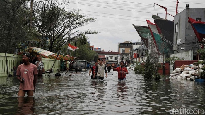 Sejumlah warga menerobos banjir komplek pergudangan galangan kapal Muara Angke, Jakarta Utara, Senin (16/12/2024).