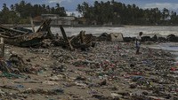 Warga berjalan di tumpukan sampah yang terbawa gelombang tinggi di Desa Teluk, Labuan, Kabupaten Pandeglang, Banten.  