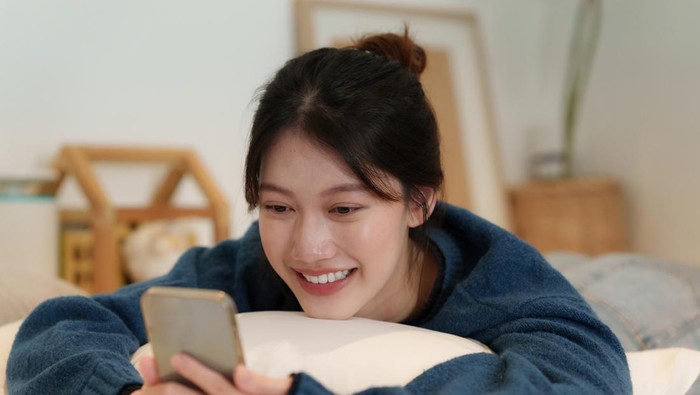 Lifestyle concept. Happy young woman using cell phone on sofa at home.