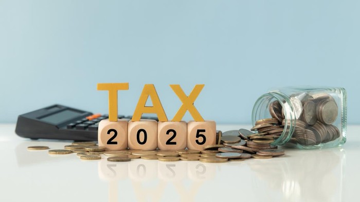 Business and tax concept. Wooden blocks spelling out TAX 2025, surrounded by coins and a calculator.  Tax deduction planning. Financial research, government taxes and calculation tax return.
