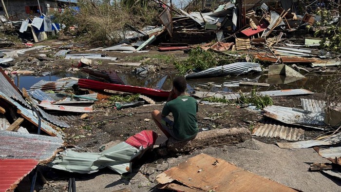 A boy sits near the ruins of homes, in the aftermath of Cyclone Chido, within Labattoir, in Mayotte, France, December 15, 2024. REUTERS/Chafion Madi