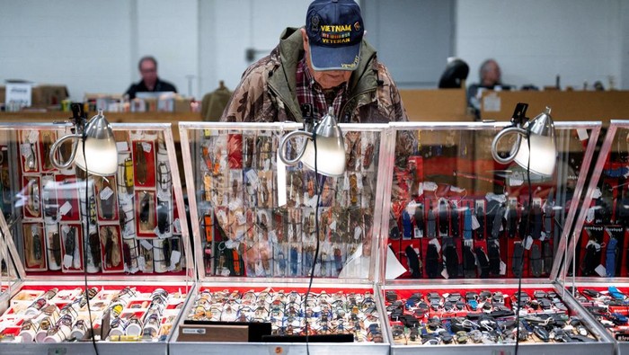 Jim Lierle, a vendor, holds a gun while speaking to a customer during the Peoria Gun & Knife Show in Peoria, Illinois, U.S. December 14, 2024.  REUTERS/Vincent Alban.  REFILE - CORRECTING TYPE OF WEAPON FROM 
