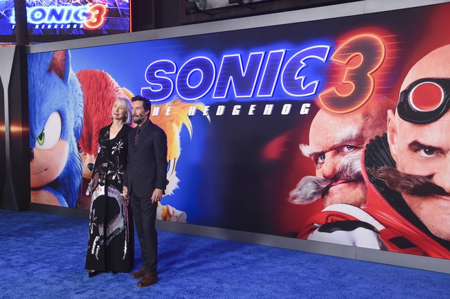 Dalam sebuah momen penuh kasih, Alexandra tampak menundukkan kepala ke bahu Keanu, seolah menyampaikan rasa cinta yang mendalam di tengah sorotan kamera. Mereka berjalan bergandengan tangan, dengan senyum ceria yang mengingatkan pada pasangan muda yang tengah jatuh cinta. (Foto: Richard Shotwell/Invision/AP)