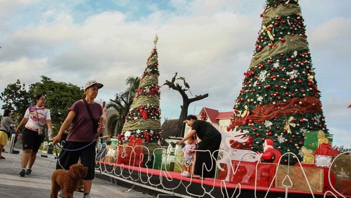 Pejalan kaki melintas di samping hiasan pohon natal di kawasan Bundaran Besar, Palangka Raya, Kalimantan Tengah, Senin (16/12/2024). Pemprov Kalteng memasang pohon dan hiasan natal sebagai tempat photobooth di kawasan tersebut guna menyambut perayaan Hari Natal dan Tahun Baru 2025. ANTARA FOTO/Auliya Rahman/Spt.