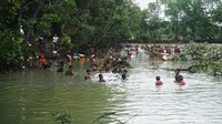 Warga dan juga petugas gotong royong memindahkan sak berisi pasir dan batu untuk meninggikan tanggul.