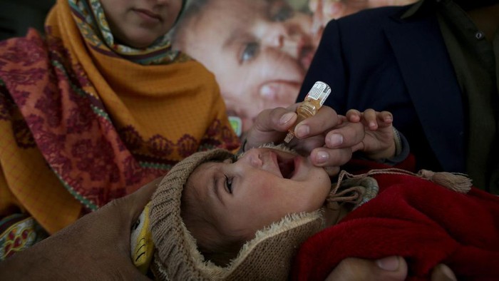 A health worker administers a polio vaccine to a child at a slum area in Lahore, Pakistan, Monday, Dec. 16, 2024. (AP Photo/K.M. Chaudary)