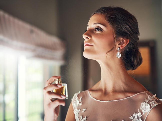 Pengantin Wanita Menyemprotkan Parfum Potret studio seorang pengantin cantik memegang sebotol parfum.