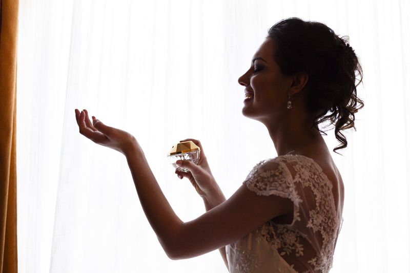 Potret studio seorang pengantin cantik memegang sebotol parfum.