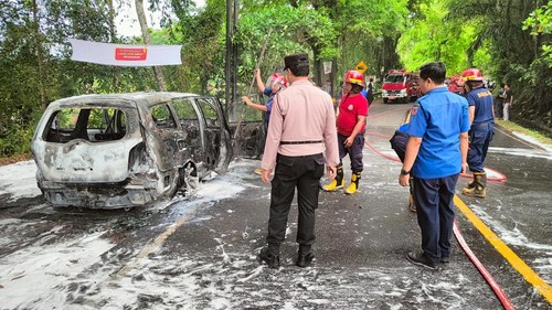 Petugas pemadam kebakaran memadamkan api yang membakar mobil di Jalan Amlapura-Singaraja, Selasa (16/12/2024).