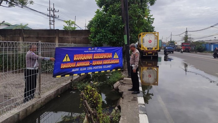 Polisi memasang banner peringatan di kawasan Surabaya Utara