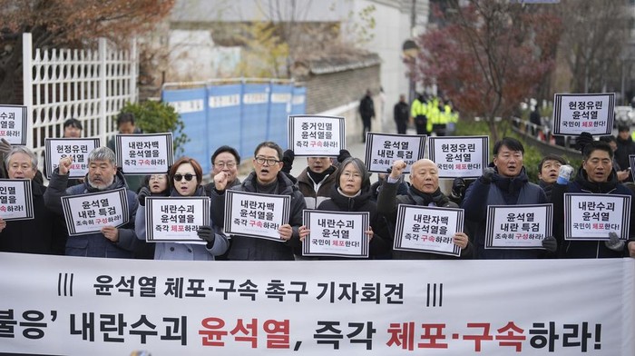 Members of civic groups shout slogans during a news conference demanding the arrest of President Yoon Suk Yeol near the presidential residence in Seoul, South Korea, Tuesday, Dec. 17, 2024. The letters read 