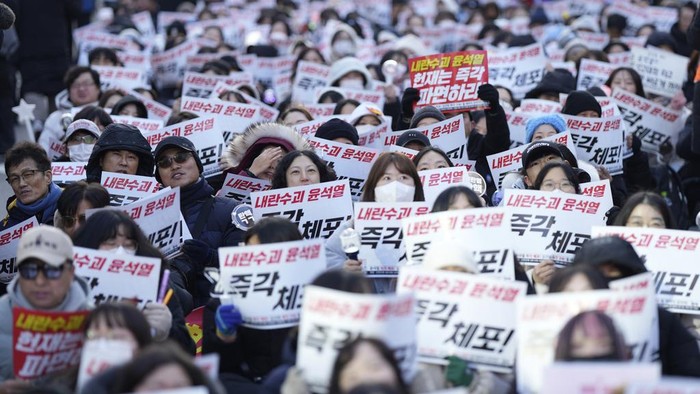 Members of civic groups shout slogans during a news conference demanding the arrest of President Yoon Suk Yeol near the presidential residence in Seoul, South Korea, Tuesday, Dec. 17, 2024. The letters read 