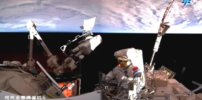Astronot Cai Xuzhe, yang terikat pada lengan robot, dan Song Lingdong, keluar dari palka Wentian, selam space walk perdana di Shenzhou-19, 17 Desember 2024.