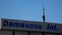 Pekerja mengganti bendera lama Suriah dengan bendera baru.  
