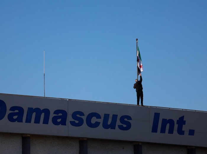 Bisnis Penerbangan di Suriah Kembali Dibuka A worker adjusts the flag adopted by the new Syrian rulers on the day the first domestic flight departs from Damascus International Airport to Aleppo International Airport during the re-opening of the airport after the ousting of Syria's Bashar al-Assad, in Damascus, Syria, December, 18 2024. REUTERS/Ammar Awad
