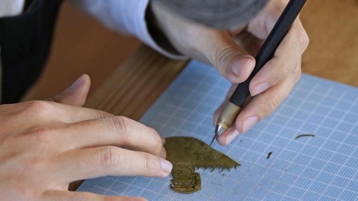 Japanese leaf-cutting artist, who goes by the name Lito, holds his freshly cut work featuring a frog with an umbrella, during an interview in Tokyo Wednesday, Nov. 27, 2024. (AP Photo/Shuji Kajiyama)