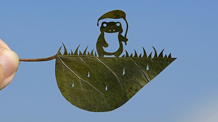 Japanese leaf-cutting artist, who goes by the name Lito, holds his freshly cut work featuring a frog with an umbrella, during an interview in Tokyo Wednesday, Nov. 27, 2024. (AP Photo/Shuji Kajiyama)