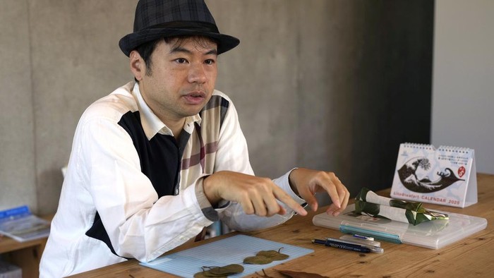 Japanese leaf-cutting artist, who goes by the name Lito, holds his freshly cut work featuring a frog with an umbrella, during an interview in Tokyo Wednesday, Nov. 27, 2024. (AP Photo/Shuji Kajiyama)