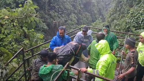 MKM (pakai mantel hitam) digendong warga saat dievakuasi dari bawah dekat Air Terjun Kuning menuju rumah sakit Bangli, Rabu (18/12/2024). (Dok. Polres Bangli)