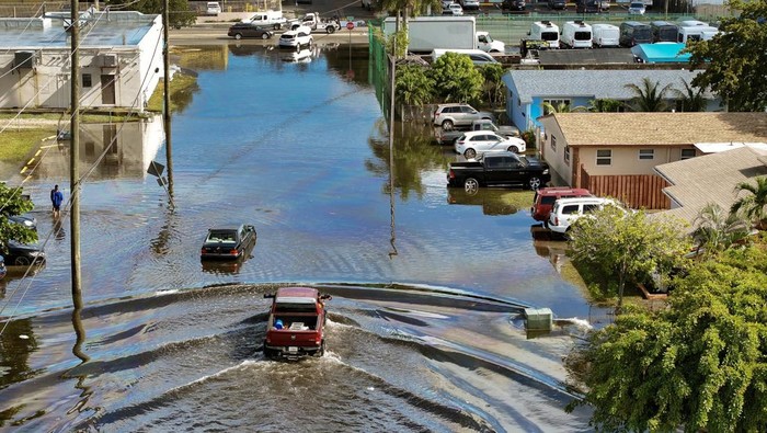 FORT LAUDERDALE, FLORIDA - DECEMBER 18: An aerial view of people driving vehicles through a flooded residential neighborhood street after localized heavy rain on December 18, 2024 in Fort Lauderdale, Florida.  Heavy rain passed through the area and flooded roads in the surrounding areas. (Photo by Joe Raedle/Getty Images)