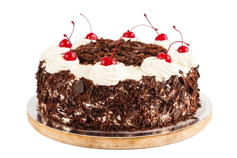 Black forest cake decorated with whipped cream and cherries. Isolated on white background
