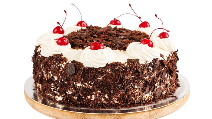 Black forest cake decorated with whipped cream and cherries. Isolated on white background