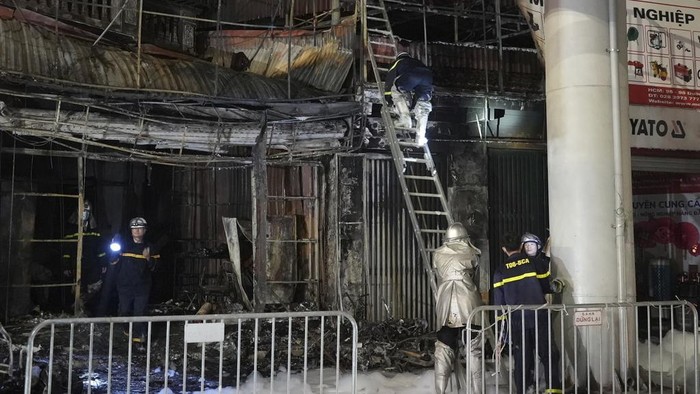Fire personnel inspect a building burned down by a fire in Hanoi, Vietnam on Thursday, Dec.19, 2024. (AP Photo/Hau Dinh)