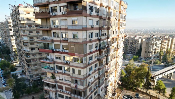 A woman shows where, according to residents, Syria's de facto leader Ahmed al-Sharaa, also known as Abu Mohammed al-Golani, lives in Damascus, Syria December 18, 2024. REUTERS/Ammar Awad