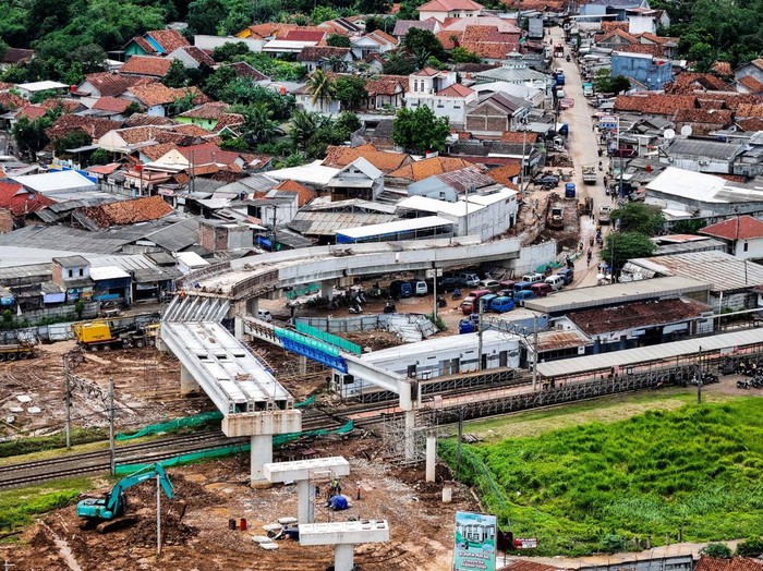 Foto udara KRL Commuter Line melintas di bawah proyek pembangunan jalan layang di kawasan Stasiun Tenjo, Kabupaten Bogor, Jawa Barat, Kamis (19/12/2024). Jalan layang sepanjang 254 meter dan jembatan penyeberangan orang senilai Rp50 miliar tersebut dibangun untuk meningkatkan penggunaan moda transportasi umum dan mengurai kemacetan di sekitar Stasiun Tenjo.