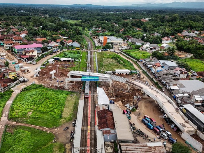 Foto udara KRL Commuter Line melintas di bawah proyek pembangunan jalan layang di kawasan Stasiun Tenjo, Kabupaten Bogor, Jawa Barat, Kamis (19/12/2024). Jalan layang sepanjang 254 meter dan jembatan penyeberangan orang senilai Rp50 miliar tersebut dibangun untuk meningkatkan penggunaan moda transportasi umum dan mengurai kemacetan di sekitar Stasiun Tenjo.