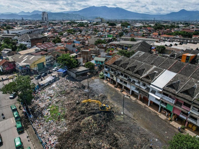 Alat berat yang dioperasikan petugas meratakan sampah yang menumpuk di Pasar Induk Caringin, Bandung, Jawa Barat, Kamis (19/12/2024). Sampah yang menumpuk berbulan-bulan di Pasar Induk Caringin tersebut disebabkan minimnya ritase angkutan sampah, dan warga berharap agar Pemerintah Kota Bandung segera menyelesaikan permasalahan itu karena bau sampah tercium hingga permukiman. ANTARA FOTO/Raisan Al Farisi/Spt.