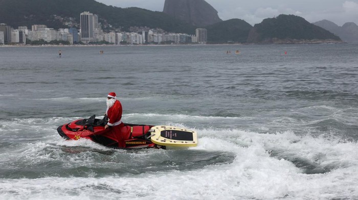 Aksi Sinterklas di Brasil Antar Hadiah Naik Jet Ski Firefighter Thiago Paiva, dressed as Santa Claus, rides on a jet ski during Christmas season celebrations in Copacabana beach in Rio de Janeiro, Brazil December 17, 2024. REUTERS/Pilar Olivares