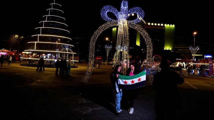 People pose for pictures by Christmas decorations in Damascus, after Syria's Bashar al-Assad was ousted, in Damascus, Syria December 19, 2024. REUTERS/Ammar Awad